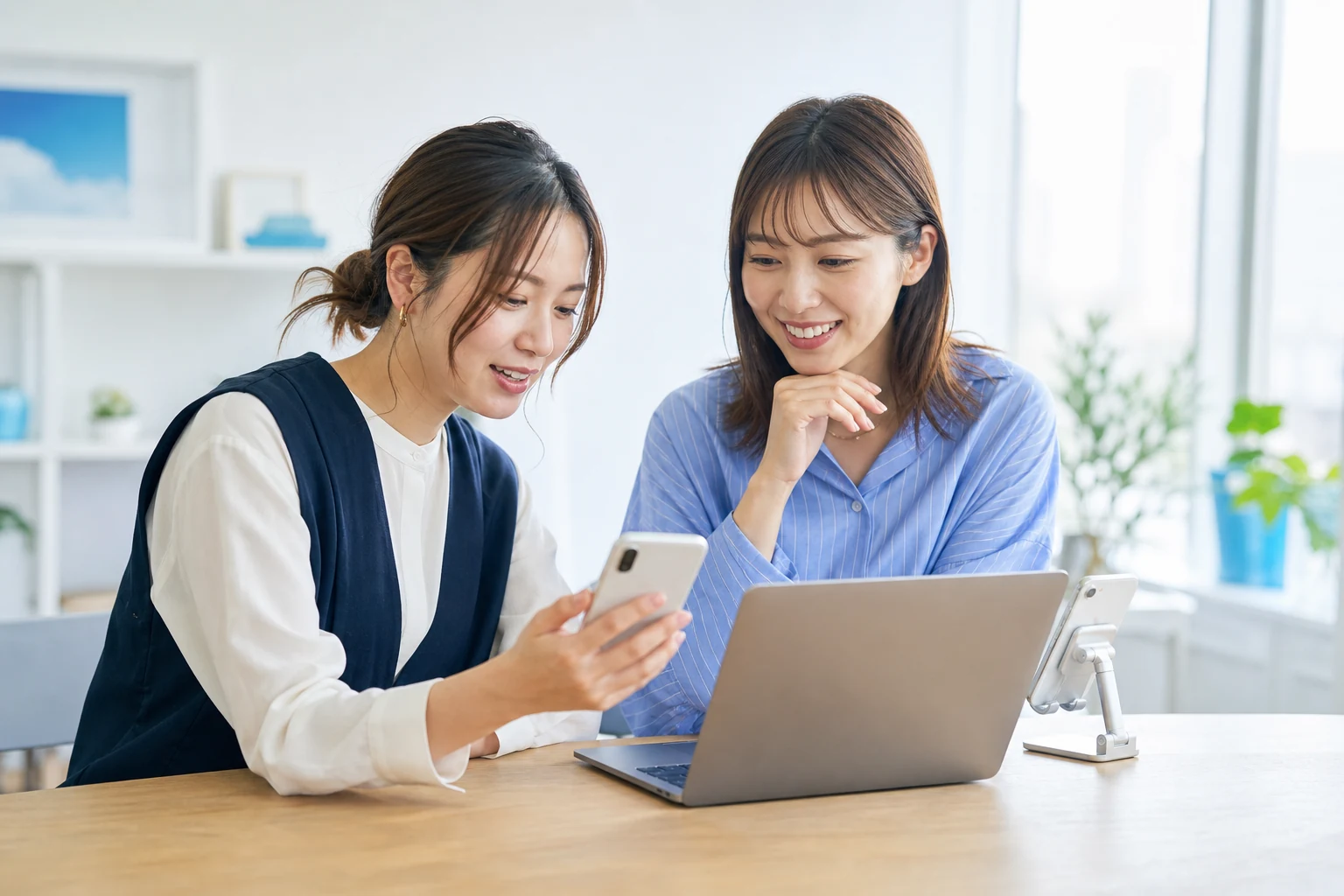 スマートフォンとノートパソコンを使ってSNS企画を相談するメンバー